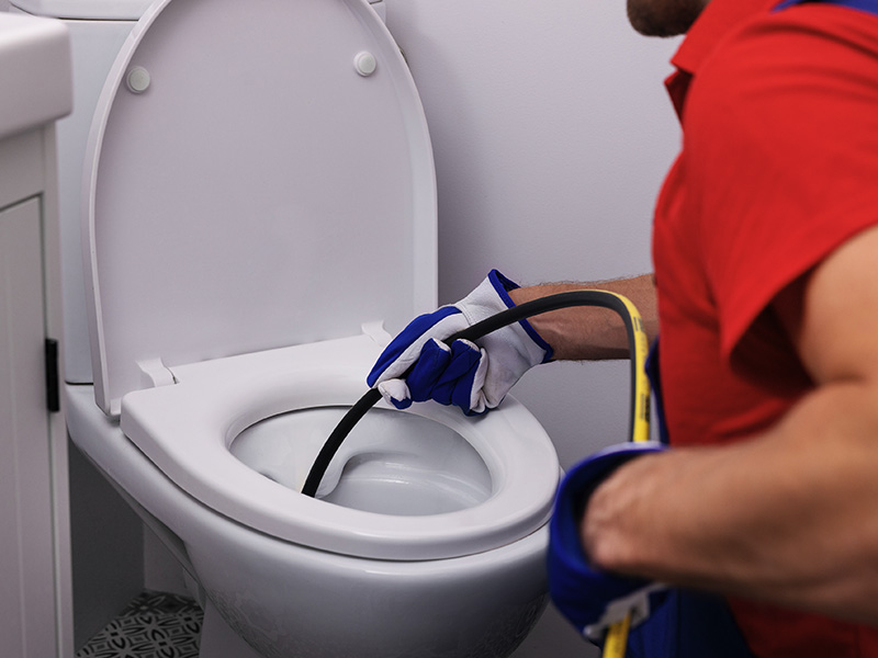 Plumber using drain snake in toilet